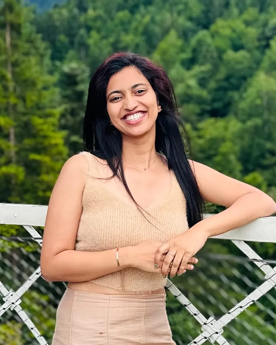 Ritty Thomas smiling on a bridge surrounded by forest
